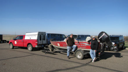 Two men next to pickup truck with boat and water sampling equipment